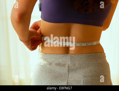 Close-up of a woman measuring her waist avec un ruban à mesurer Banque D'Images