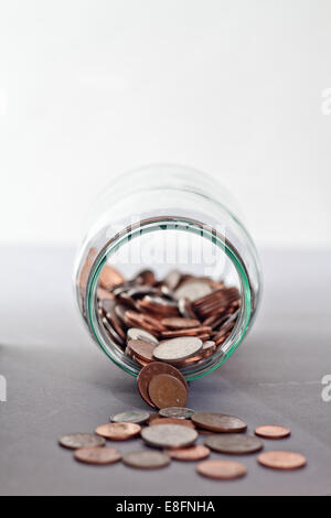 Gros plan de pièces de monnaie se déversant d'un pot en verre sur une table Banque D'Images