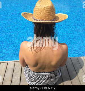 Vue arrière de femme assise au bord d'une piscine Banque D'Images