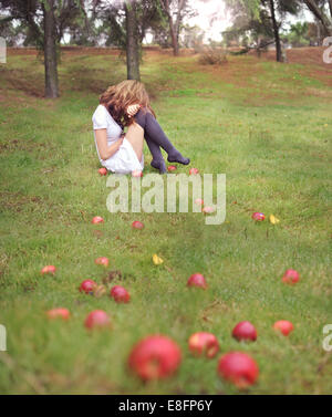 Femme assise dans un jardin à côté de pommes tombées, Espagne Banque D'Images