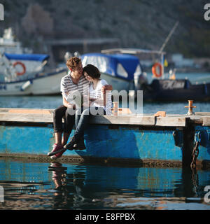 Couple (14-15) sitting on Jetty, embracing Banque D'Images