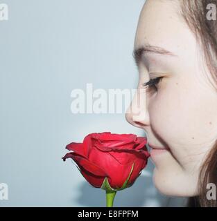 Close-up portrait of a woman with eyes closed smelling a fleur rose Banque D'Images