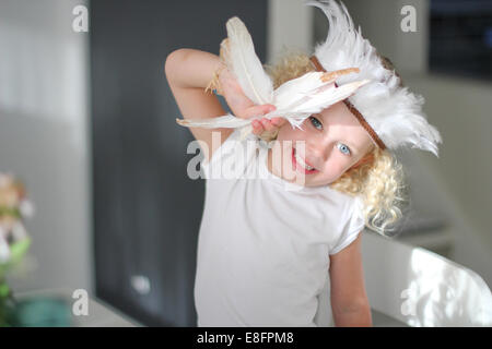 Portrait de jeune fille portant une coiffe de plumes plumes holding Banque D'Images