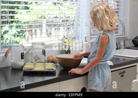 Girl standing in kitchen baking cakes Banque D'Images