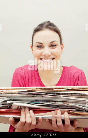 Jeune femme tenant une pile de journaux Banque D'Images