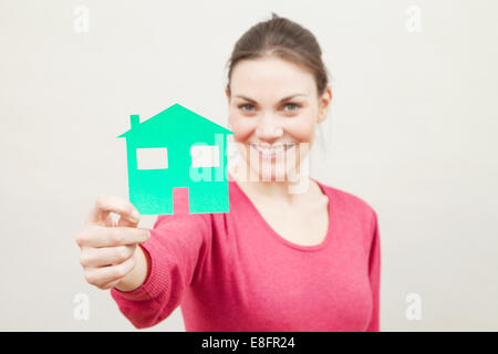 Young woman holding paper cut out d'une maison Banque D'Images