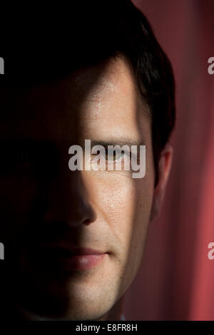 Close-up portrait d'un homme avec la moitié de visage caché dans l'obscurité Banque D'Images