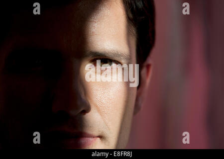 Close-up portrait d'un homme avec la moitié de visage caché dans l'obscurité Banque D'Images