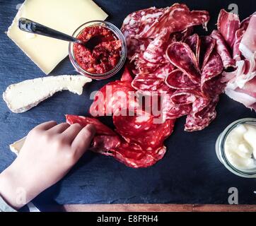 La main de l'atteindre pour la charcuterie et fromages Banque D'Images