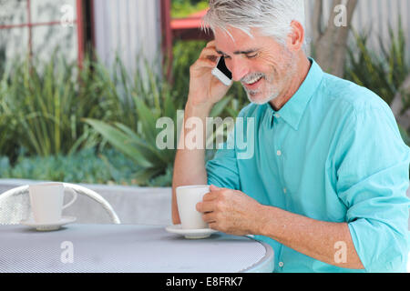 Businessman having tasse de café tout en parlant au téléphone Banque D'Images