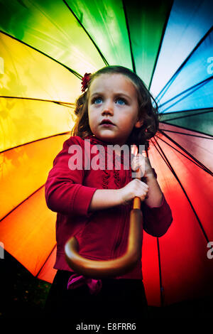 Portrait d'une fille tenant un parapluie multicolore arc-en-ciel Banque D'Images