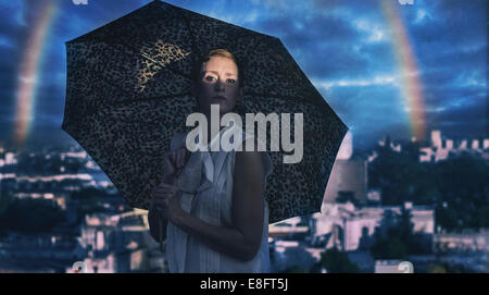 Femme debout à l'extérieur avec un parapluie et un arc-en-ciel en arrière-plan, l'Argentine Banque D'Images