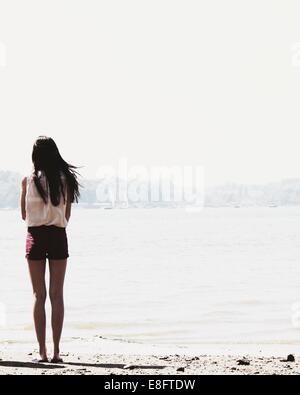 Vue arrière du teenage Girl standing on beach looking at view