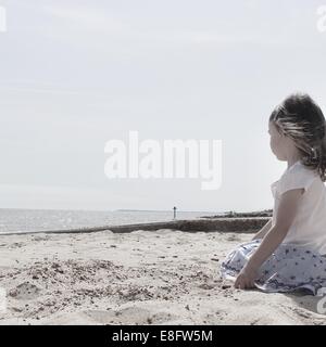 Fille assise sur la plage
