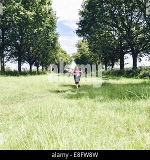 Boy running through field holding Union Jack flag Banque D'Images