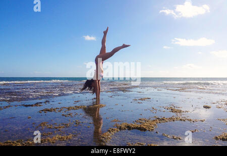 Woman doing handstand on beach Banque D'Images