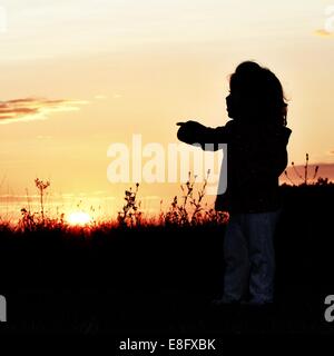 Silhouette de jeune fille debout dans un champ indiquant Banque D'Images