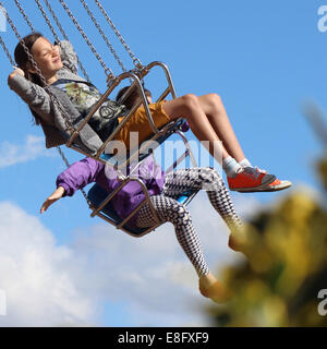 Deux filles sur des balançoires carrousel de foire au Banque D'Images