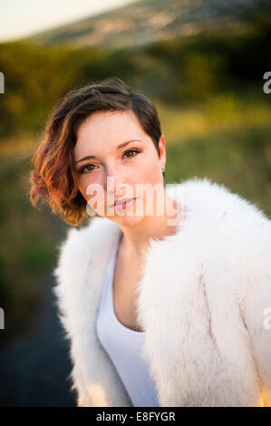 Un jeune androgyne aux yeux de biche à teenage femme fille portant une veste courte fourrure blanche, seul en plein air, soirée d'UK Banque D'Images