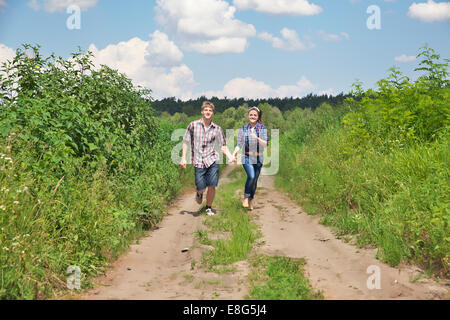 Jeune couple en marche le long de la route de champ Banque D'Images