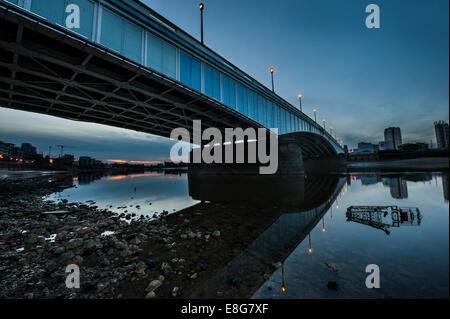 Un chariot de supermarché sous-évaluées sous un pont de la Tamise à marée basse Banque D'Images