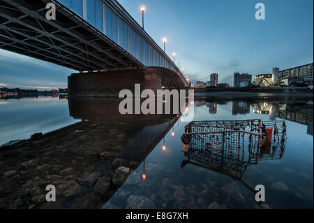 Un chariot de supermarché sous-évaluées sous un pont de la Tamise à marée basse Banque D'Images