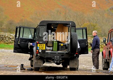 Land Rover Defender garé avec toutes les portes ouvertes et truffée de vitesse sur un parking de gravier dans le Lake District Banque D'Images