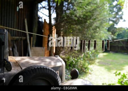 Une ligne de vieilles chevilles en bois sur une ligne de lavage, avec un vieux camion rouillé dans l'arrière-plan Banque D'Images