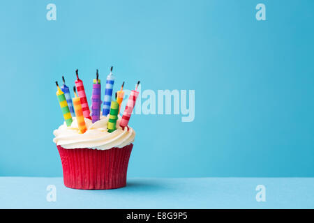 Birthday cupcake avec bougies soufflées sur un fond bleu Banque D'Images