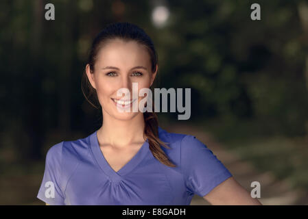 Smiling attractive young woman wearing a blue t-shirt debout à l'extérieur dans l'obscurité regardant la caméra, avec copie espace Banque D'Images