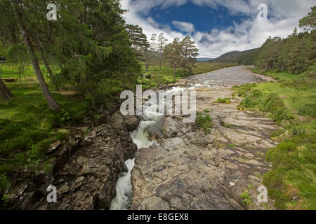 De l'eau Rivière Dee se précipiter à travers gorge rocheuse étroite entourée par le vert émeraude de l'herbe et forêt de pins sous ciel bleu à Linn o' Dee en Ecosse Banque D'Images