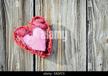 Rose rouge coeur à la main avec motif décoratif décoration extérieur accrocher par aiguille sur fond de bois Banque D'Images