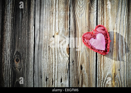 Rose rouge coeur à la main avec motif décoratif décoration extérieur accrocher par aiguille sur fond de bois Banque D'Images