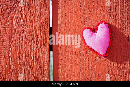 Décoration coeur fait main rose avec motif ornemental en dehors de pendre par aiguille sur fond de bois rouge Banque D'Images