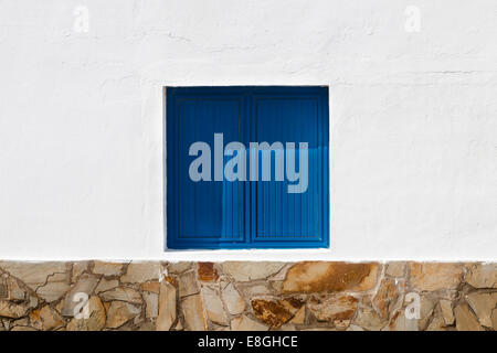 Une fenêtre avec des volets bleus en mur blanc Banque D'Images