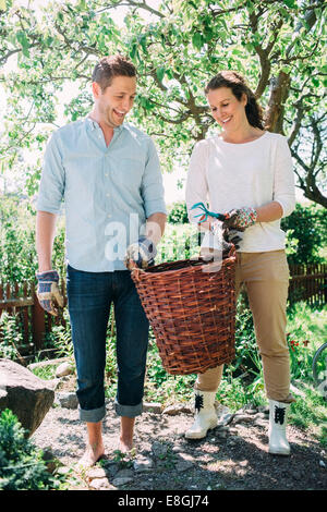 Heureux couple carrying panier en osier tout en faisant du jardinage à la cour Banque D'Images