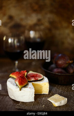 Gros plan d'une roue de fromage brie avec des figues fraîches et du vin rouge sur une table Banque D'Images