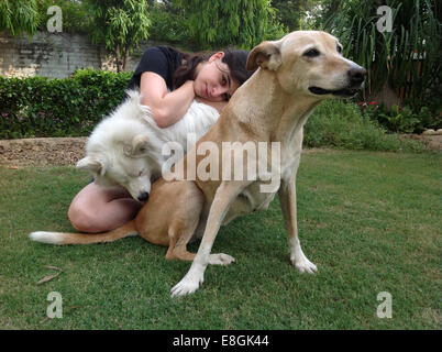 L'Inde, New Delhi, jeune femme assise dans un jardin avec deux chiens Banque D'Images