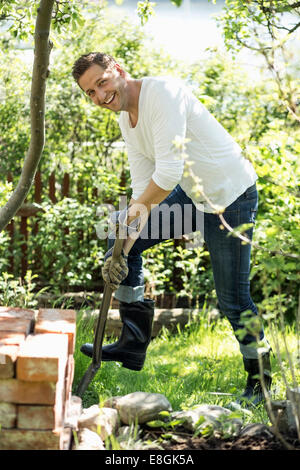 Vue de côté portrait of happy man gardening at yard Banque D'Images