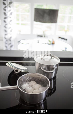 Faire bouillir les oeufs dans la casserole sur la cuisinière dans la cuisine Banque D'Images