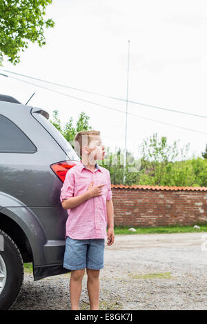 Boy standing in front of car on street Banque D'Images