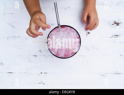 Les mains de l'enfant pour atteindre le strawberry milkshake avec bulles Banque D'Images