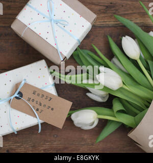 Vue en hauteur d'un bouquet de tulipes blanches et de cadeaux enveloppés pour la fête des mères sur une table Banque D'Images