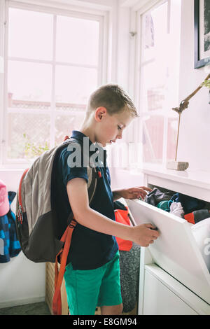 School boy à la recherche de vêtements dans le tiroir à la maison Banque D'Images