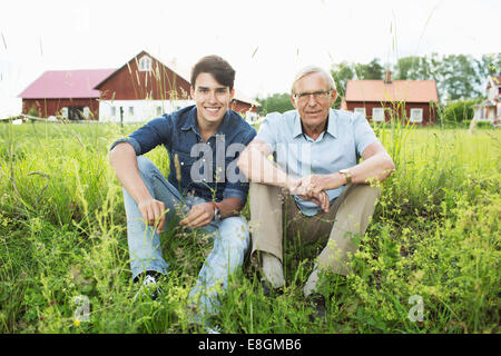 Portrait de grand-père et petit-fils assis sur les champs Banque D'Images