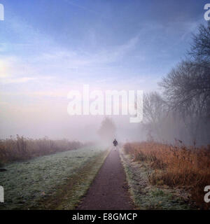 Vue arrière d'un homme qui marche sur le sentier le matin brumeux Banque D'Images