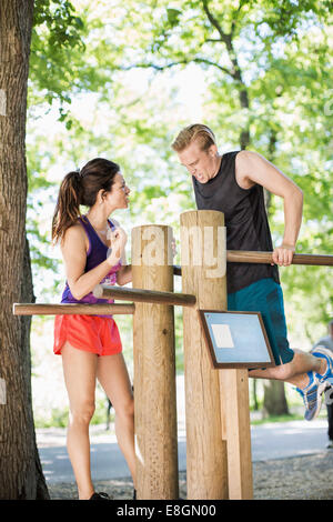 Femme Homme motivant ce faisant chin-ups sur barres de bois au club de plein air Banque D'Images