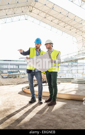 Des experts discutant sur blueprint at construction site Banque D'Images