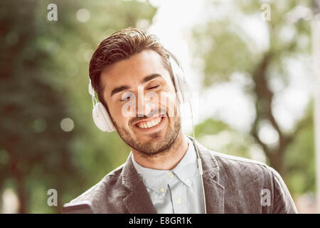 Businessman profiter de la musique à travers des écouteurs à l'extérieur Banque D'Images