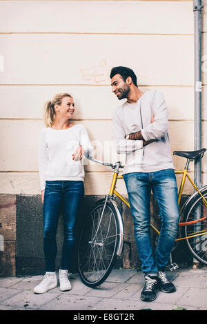 Les amis de communiquer tout en se tenant en vélo sur un trottoir Banque D'Images